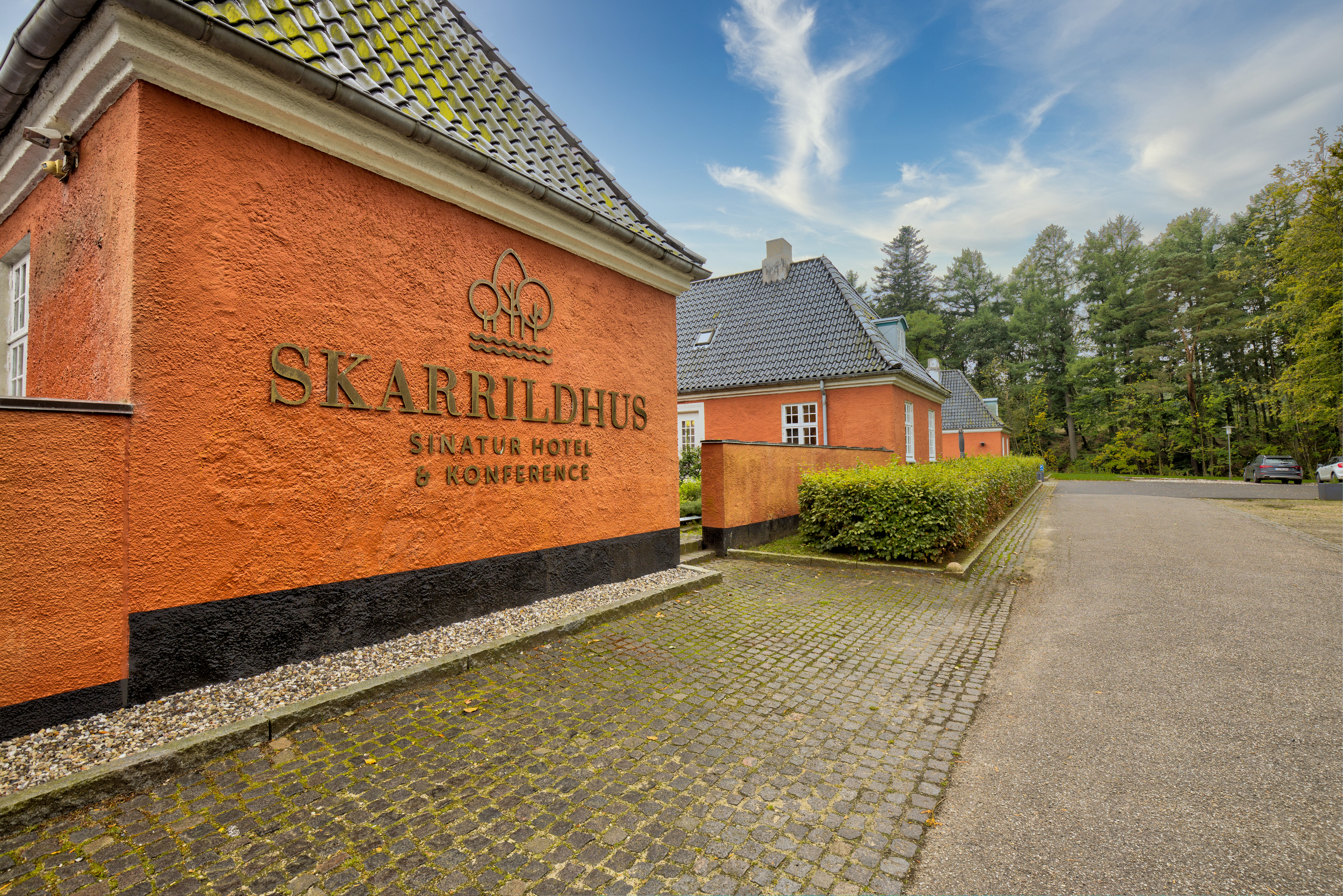 Skarrildhus udenfor med Sinatur logo